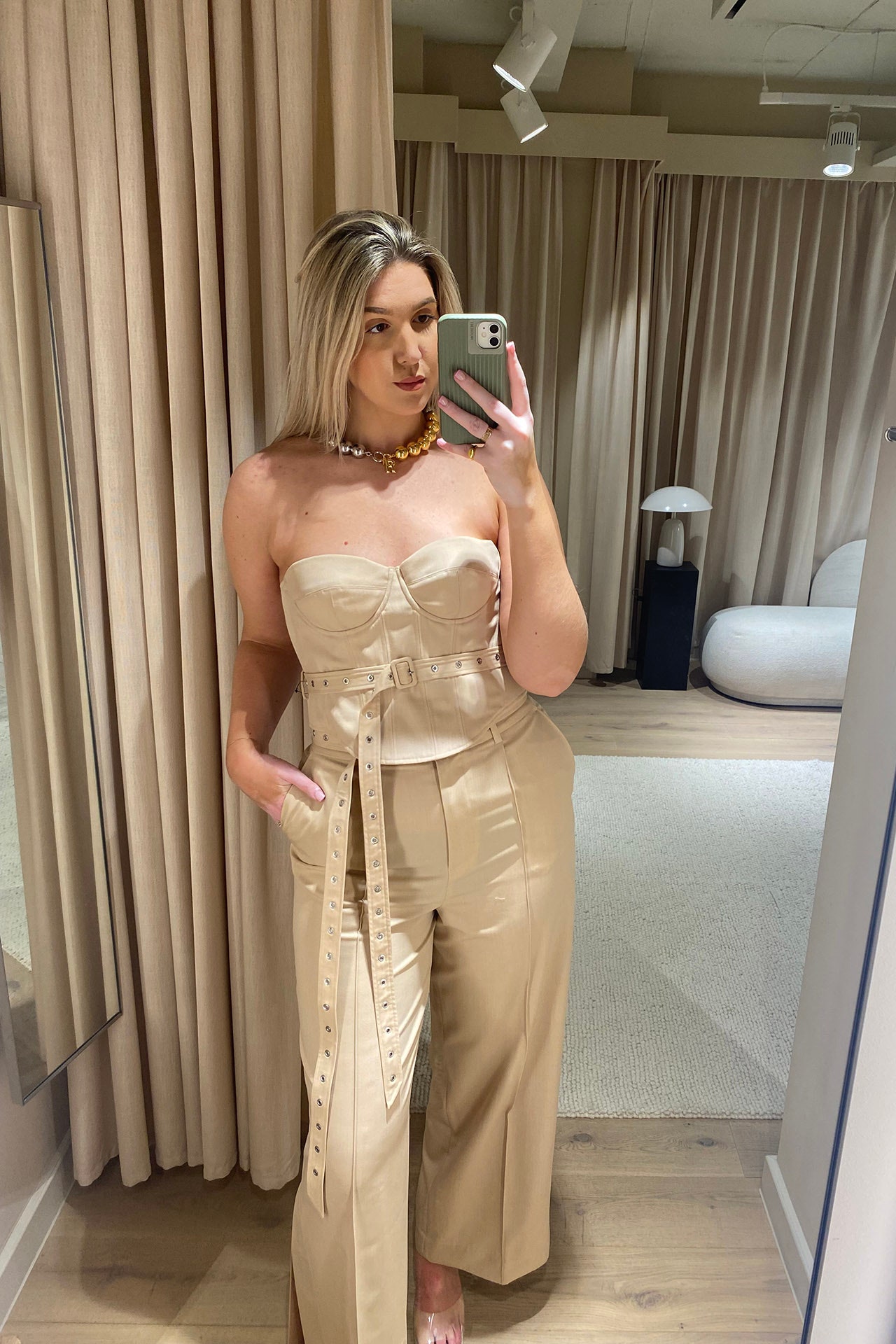 Image may contain Adult Person Clothing Dress Blonde Hair Accessories Jewelry Necklace Sleeve and Lamp